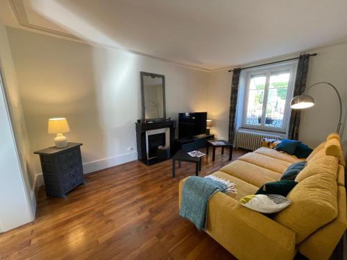 a living room with a yellow couch and a mirror at La maison des douceurs in Bussang