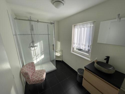 a bathroom with a shower and a chair and a sink at La maison des douceurs in Bussang