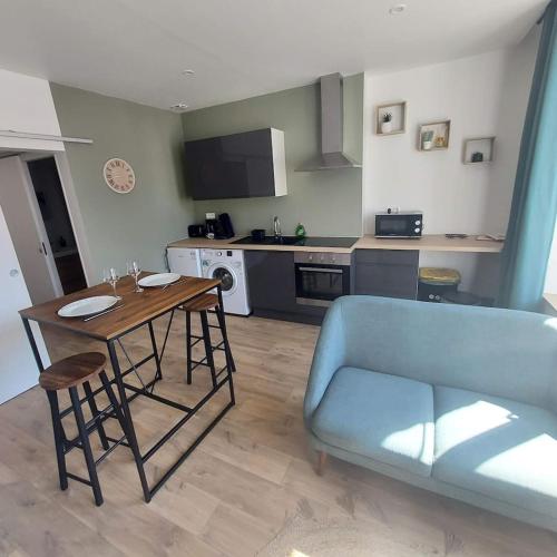 ein Wohnzimmer mit einem Tisch und einem blauen Sofa in der Unterkunft Joli appartement F2 plein centre Coutances in Coutances