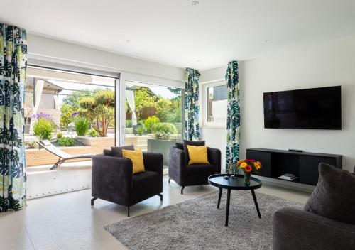 a living room with two chairs and a tv and a table at Domizil Relax - Seeluft in Überlingen