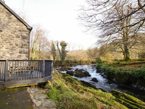 a river next to a building with a bench next to it at Pen y Bont in Machynlleth