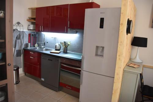 een keuken met rode kasten en een witte koelkast bij Gite VIANY 1 in La Tour-dʼAigues