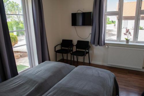 1 dormitorio con 1 cama, 2 sillas y ventanas en Nordgården Pension, en Onsbjerg