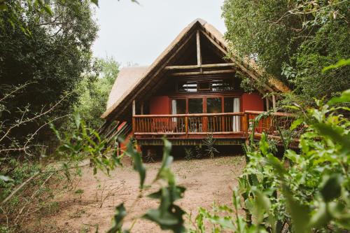 a red house with a balcony in the forest at Hluhluwe River Lodge in Hluhluwe