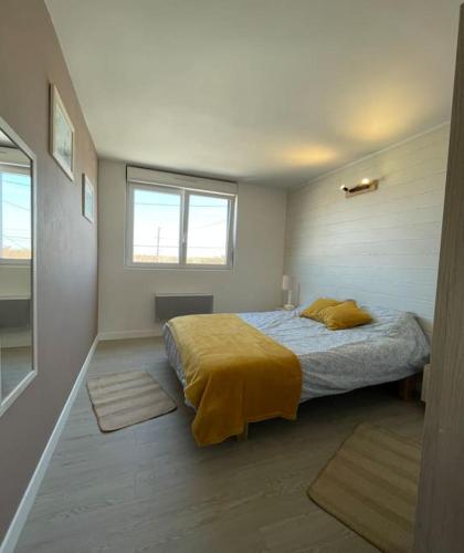 een slaapkamer met een bed met een gele deken bij T3 6 pers. - La Tranche sur mer in La Tranche-sur-Mer