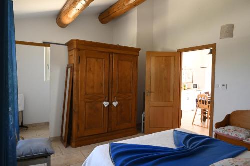 a bedroom with a wooden cabinet and a bed at Gîte Bienvenue Chez Nous in Ménerbes