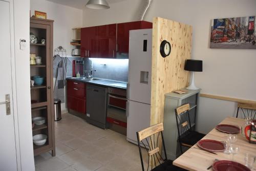 een keuken met rode kasten, een tafel en een koelkast bij Gite VIANY 1 in La Tour-dʼAigues