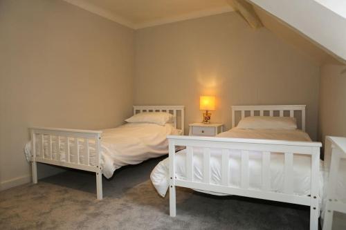 two white beds in a room with two lamps at Cosy Modern Cottage - Wareham in Wareham
