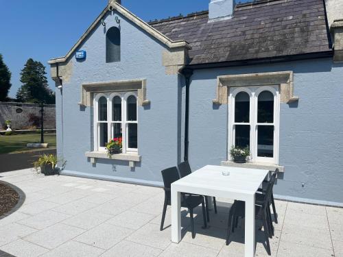 una mesa blanca y sillas frente a una casa azul en Wellington Cottage en Wexford