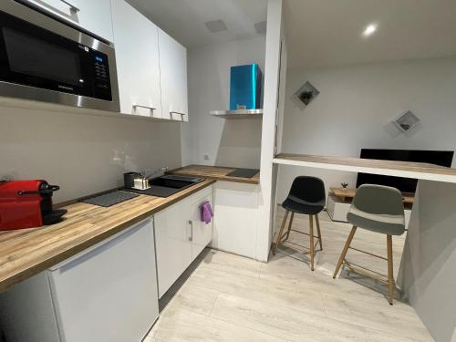 une petite cuisine avec un comptoir et deux tabourets dans l'établissement Appartement T2 moderne au cœur des Minimes, à La Rochelle