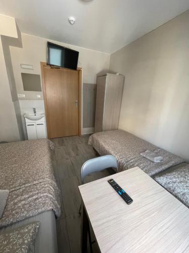 a room with two beds and a table and a tv at Lawendowy Hostel Wrocław in Wrocław