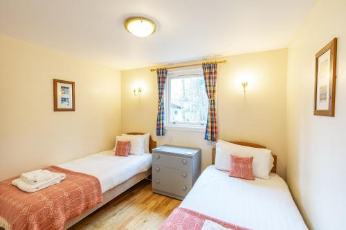 a bedroom with two beds and a window at Bracken Lodge 8 with Hot Tub in Belladrum