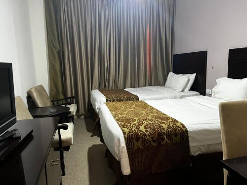 a hotel room with two beds and a television at Shepherd Hotel in Amman