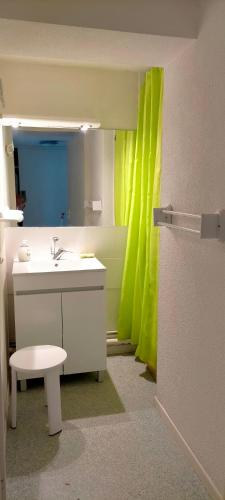 La salle de bains est pourvue d'un lavabo et d'un rideau de douche jaune. dans l'établissement Cap Soleil T3 proche plage, au Cap d'Agde