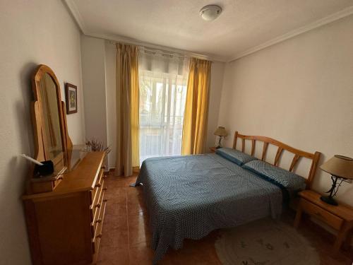 - une chambre avec un lit, une commode et un miroir dans l'établissement Apartamento Pascual, à Torrevieja