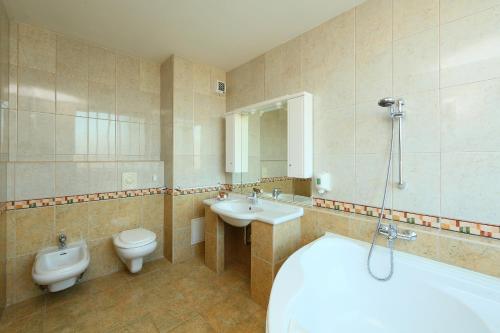 a bathroom with a tub and a toilet and a sink at Hotel Margareta in Balatonfüred