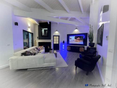 een woonkamer met een witte bank en een tv bij Grande villa Calme & Piscine Rochelle / île de Ré in Dompierre-sur-Mer