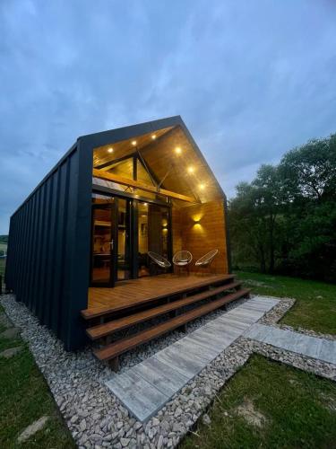 a small black house with a deck and chairs at Mini Valley House 1 in Sita Buzăului