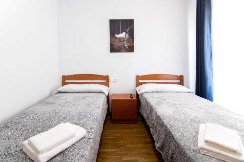 2 łóżka w małym pokoju z ręcznikami w obiekcie Yani's Hospedaje w mieście Arriondas