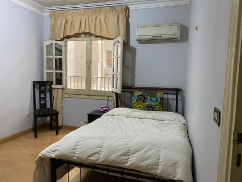 1 dormitorio con cama, ventana y silla en Cozy private room @ SWEET HOME, en El Cairo