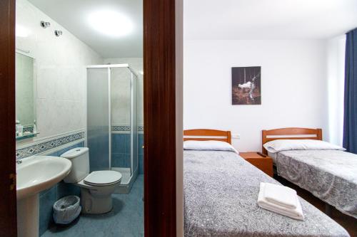 łazienka z 2 łóżkami, prysznicem i umywalką w obiekcie Yani's Hospedaje w mieście Arriondas