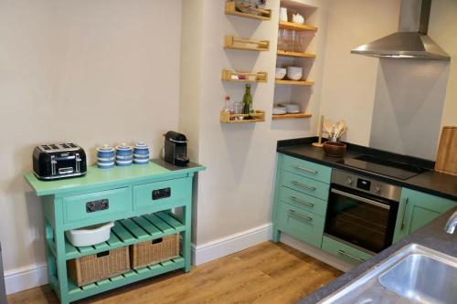 a kitchen with green cabinets and a sink at Bumblebee cottage Exmouth in Exmouth
