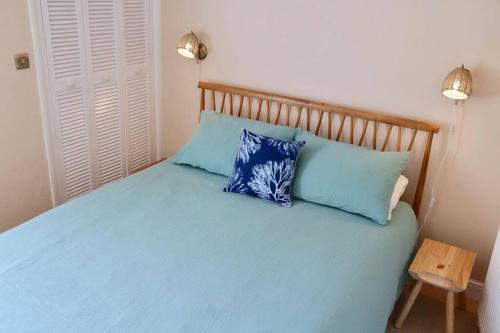 a bedroom with a blue bed with two blue pillows at Bumblebee cottage Exmouth in Exmouth