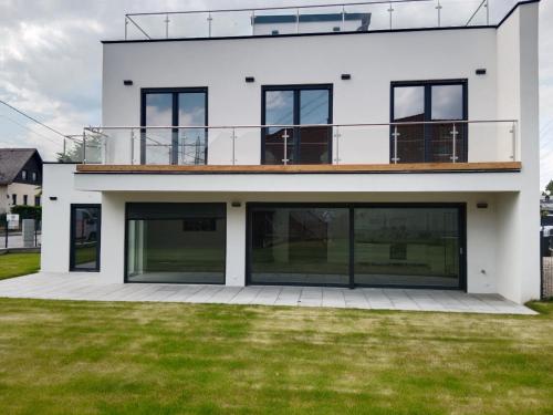 uma casa branca com janelas grandes e uma varanda em Haus mit Garten bei Wien em Langenzersdorf