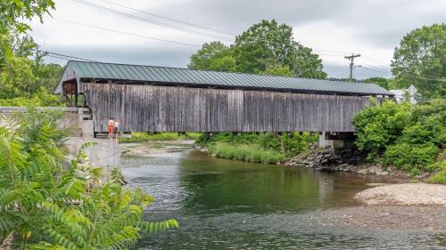 acovered bridge over a river with a man standing under it at Robinson Cabin cabin in Warren
