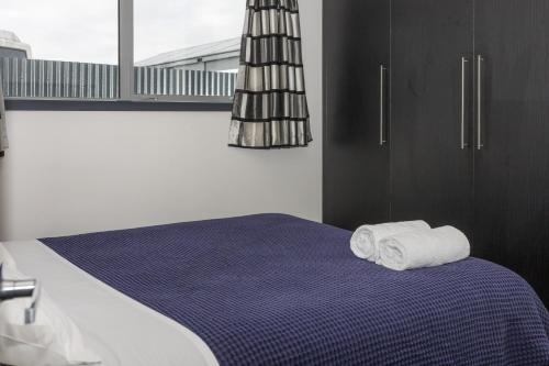 a bedroom with a bed with two towels on it at Modern on McMillan in Methven
