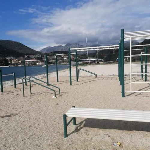 a park with a bench and poles and water at Studio apartman Endy in Ploče