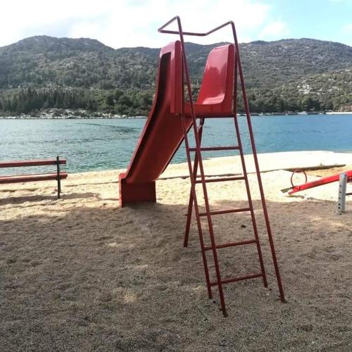 a red slide on the beach next to the water at Studio apartman Endy in Ploče