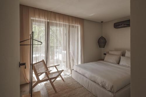 a bedroom with a bed and a chair and a window at Hill Palanga & SPA in Palanga
