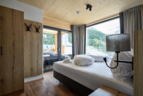 um quarto com uma cama e uma grande janela em Alm-Lodges Montafon em Gargellen