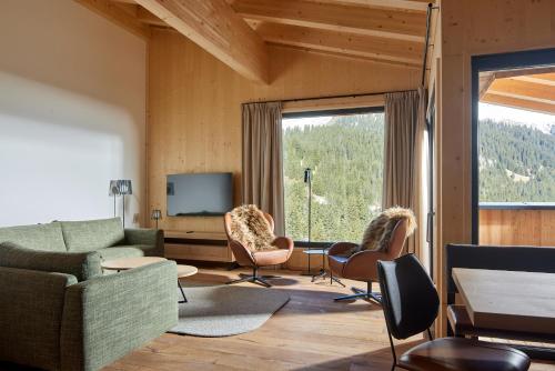 a living room with a couch and chairs and a tv at Alm-Lodges Montafon in Gargellen