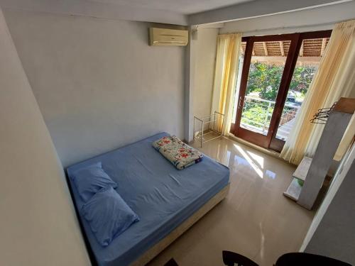a bedroom with a blue bed in a room with a window at Kanaan House in Nusa Dua
