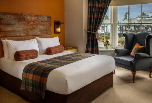 um quarto de hotel com uma cama e uma cadeira e uma janela em The Crown Inn Pooley Bridge em Pooley Bridge