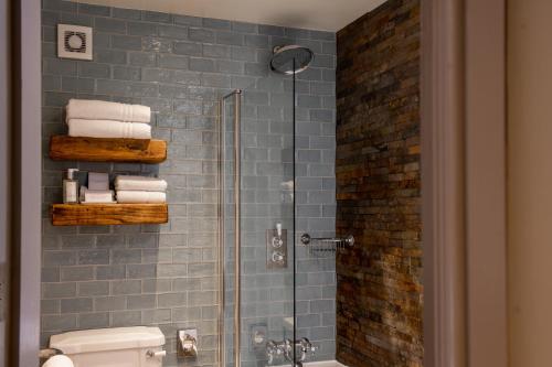 a bathroom with a glass shower with a toilet and towels at The Crown Inn Pooley Bridge in Pooley Bridge