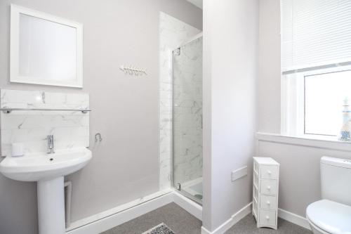 a white bathroom with a shower and a sink at The Skipper's House in Weymouth