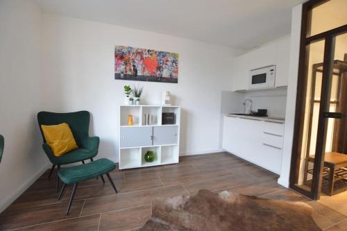 een woonkamer met een groene stoel en een keuken bij Studio 7 City Lage mit Garage nähe Köln Bonn in Siegburg
