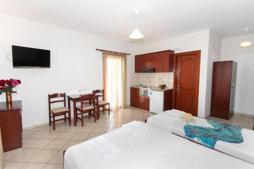 1 dormitorio con 2 camas y cocina con mesa en Lady Elena Hotel en Ammoudia