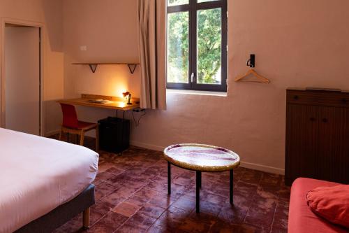 a bedroom with a bed and a stool and a window at Hôtel La Prison in Béziers