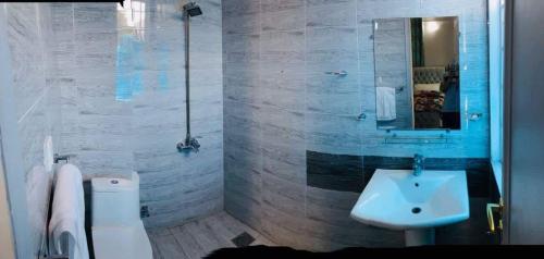 een badkamer met een wastafel, een toilet en een spiegel bij Rio Inn Guest House in Islamabad