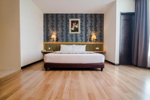 ein Schlafzimmer mit einem Bett und zwei Tischen mit Lampen in der Unterkunft De' Garden Hotel, Butterworth in Butterworth