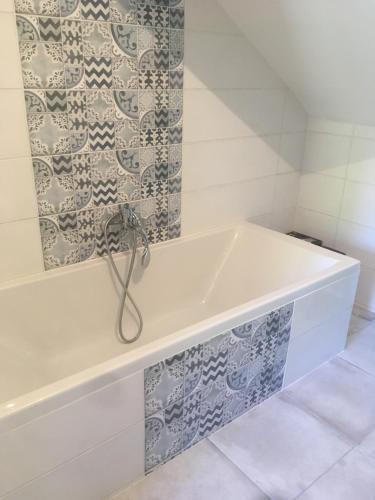 a bath tub in a bathroom with a tile wall at Maison familiale avec piscine à 3km de la plage in Latour-Bas-Elne