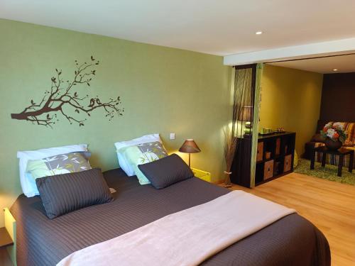 une chambre avec un lit avec une branche sur le mur dans l'établissement La maison des roses, à Chadrac