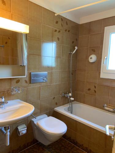 La salle de bains est pourvue de toilettes, d'un lavabo et d'une baignoire. dans l'établissement Bed and Breakfast Darlux, à Bergün