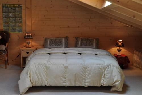 een slaapkamer met een wit bed en een houten muur bij Ovronnaz, le vieux Mazot in Chamoson
