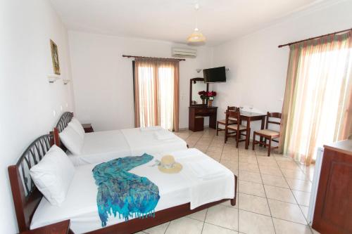 a bedroom with a white bed and a dining room at Lady Elena Hotel in Ammoudia