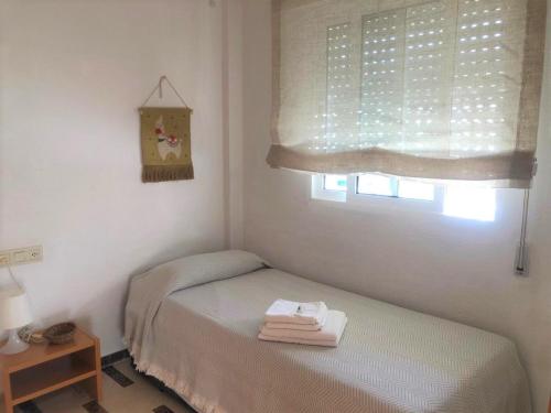 a small bedroom with a bed and a window at Acogedor apartamento frente al mar con piscina in Altea